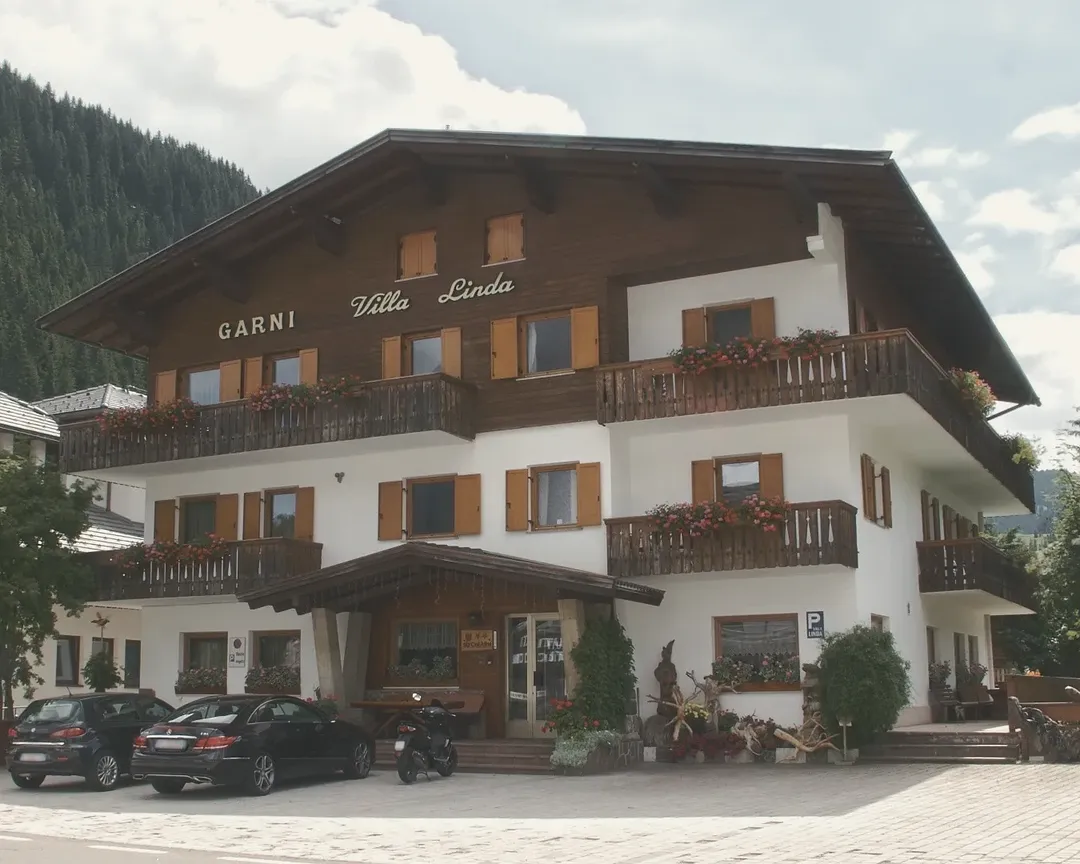 La facciata del Garni Villa Linda, con balconi in legno e gerani rossi